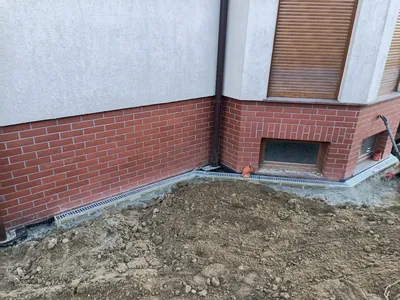 Korytka odwodnienia liniowego zamontowane przy ścianie fundamentowej